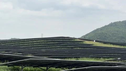 Rows of solar panels trace the natural contours of a hillside, forming Stock Footage 322514944