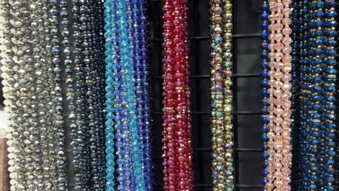 Rows of sparkling multicolored beads hang in vertical strands on display 스톡 동영상 321341682