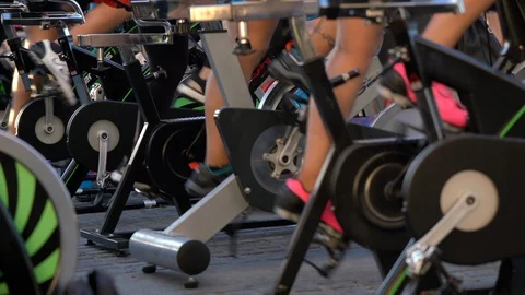 Rows of spin bikes lined up in an outdoor setting as cyclists spin the pedals. Stock Footage 127894326