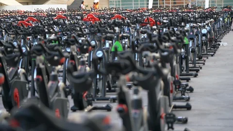 Rows of spin bikes lined up in an outdoor setting before the riders take to them Stock Footage 127894625