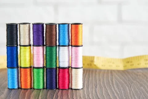 Rows of spools of colorful sewing threads and measuring tape on the table Stock Photos