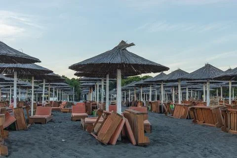 Rows of Straw Umbrellas and Folded Sunbeds at Velipoja Dusk Stock Photos