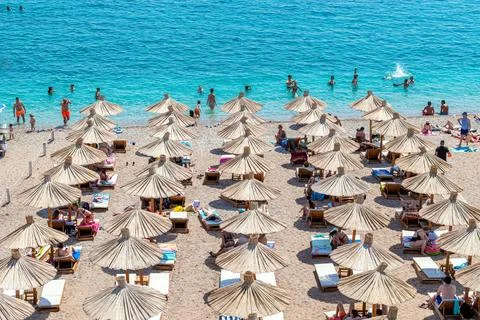 Rows of straw umbrellas line the pebble beach zone Stock Photos