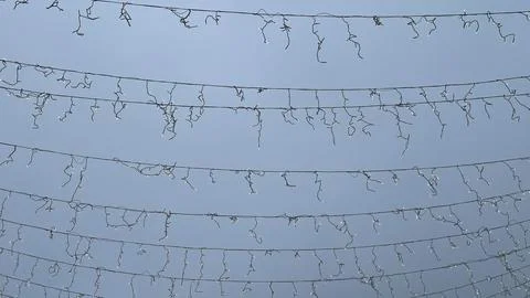Rows of stretched light cables and disconnected garland against a clear blu.. Stock Photos