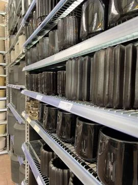 Rows of stylish ceramic and stone planters fill the shelves in a home goods s Stock Photos