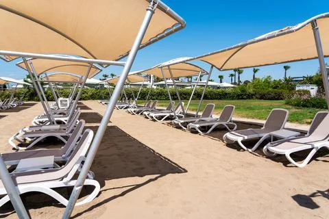 A rows of sunbeds at a deserted sandy beach in turkish resort. Sun loungers Stock Photos
