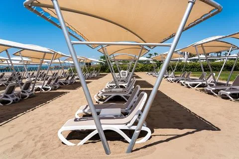 A rows of sunbeds at a deserted sandy beach in turkish resort. Sun loungers Stock Photos