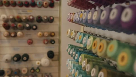 Rows of threads on spools at the stands in a sewing workshop or atelier are Stock-Footage 151766271