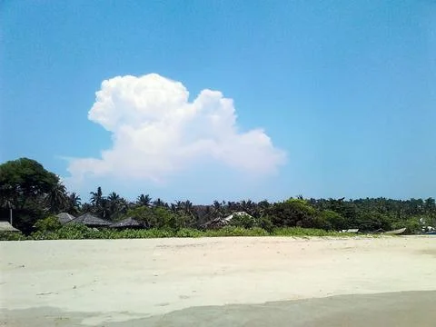 Rows of trees and huts seen from the sandy beach Stock Photos