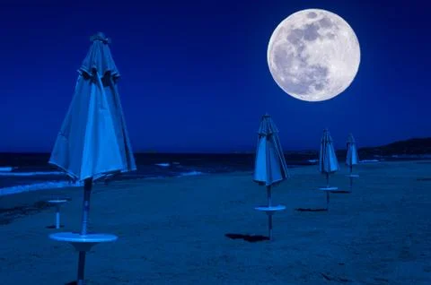 Rows of umbrellas and deck chairs on the beach at night Stock Photos