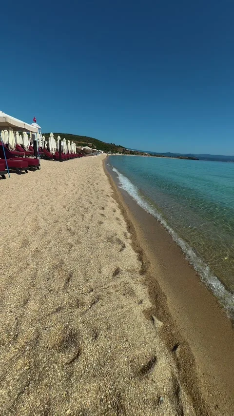 Rows of umbrellas line the beach, ready for sun. Trani Ammouda, Greece. Vertical Stock Footage 339629156