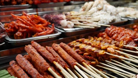 Rows of uncooked meat skewers placed across a market display surface prepared fo Видео 338001513