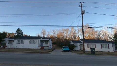 Rows of urban duplex businesses and homes on Lumpkin road passing traffic cle Stock Footage 152170868