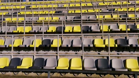 Rows of vacant stadium seats adorned in vibrant yellow and muted gray colors Stock Footage 306062081
