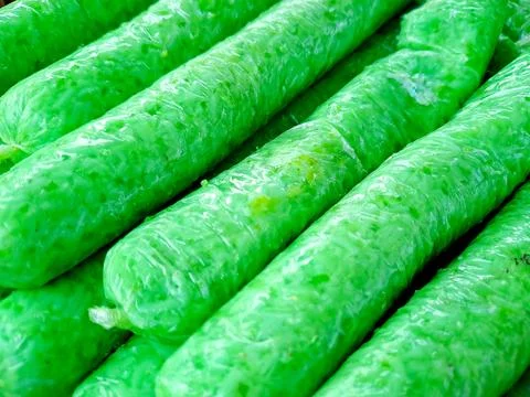 Rows of vibrant green translucent sausages bundled closely together in a co.. Stock Photos