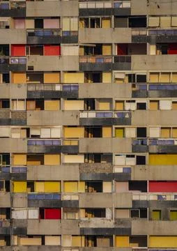 Rows of weathered concrete balconies with multicolored doors cover the faca.. Stock Photos