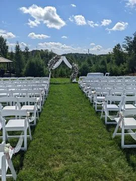 Rows of white chairs are lined up and in an outdoor wedding ceremony setting Stock Photos