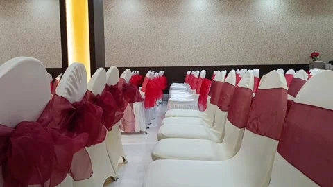 Rows of white chairs with red sashes set up in a banquet hall, ideal for event p Stock-Footage 333117118
