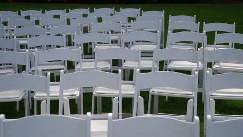 Rows of White Folding Chairs on Green Grass for Outdoor Event Stock Footage 295008683