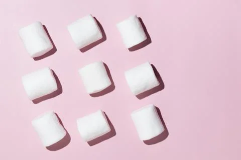 Rows of white marshmallows pattern on light pink table background in hard l.. Stock Photos