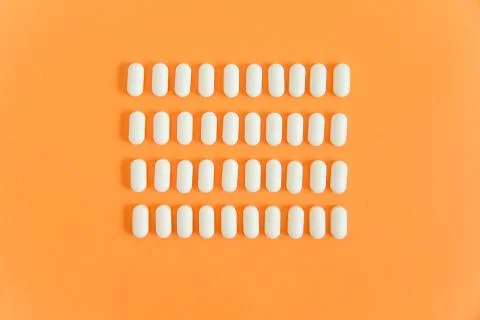 Rows of white pills on an orange background Stock Photos