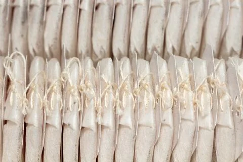 Rows of white tea bags with strings and tags arranged in a pattern 스톡 사진