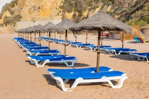 Rows of wicker parasols and beach beds Stock Photos