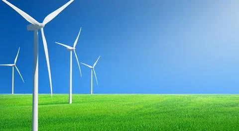 Rows of wind generators on a field of green grass against blue sky Stock Photos