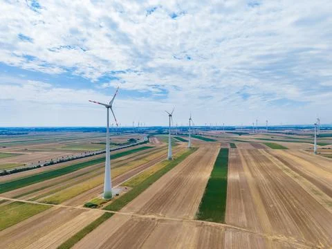 Rows of wind turbines are seen on a sunny day in the countryside. The fields  Stock Photos