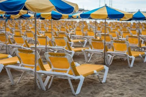 Rows of yellow sunbeds with blue and yellow parasols at the beach Playa de Stock Photos