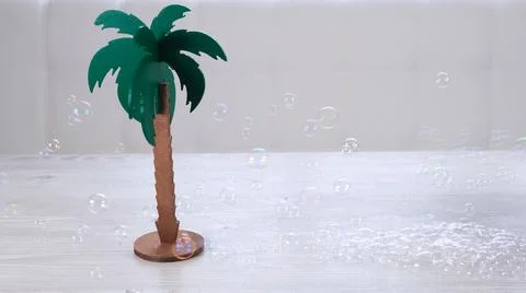 Rtificial palm tree and rainbow soap bubbles on a white wooden table. Relaxation Stock Photos