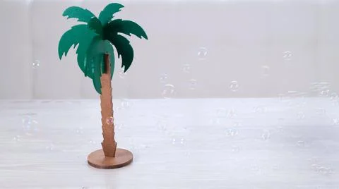 Rtificial palm tree and rainbow soap bubbles on a white wooden table. Relaxation Stock Photos