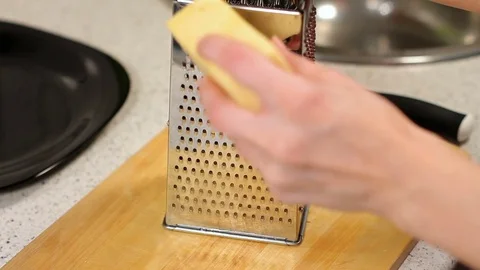 Rub cheese on a grater on kitchen table. crushing of cheese. Woman grating Stock Footage 78567971