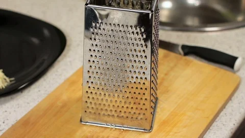 Rub cheese on a grater on kitchen table. crushing of cheese. Woman grating 動画素材 78568144