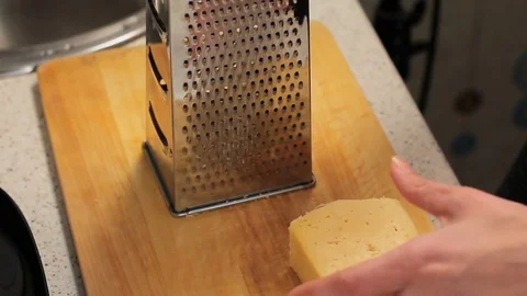 Rub cheese on a grater on kitchen table. crushing of cheese. Woman grating 動画素材 78568277