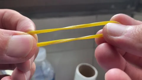 Rubber band and pulling elastic tugging on a rubber band between hands Stock Footage 250063344