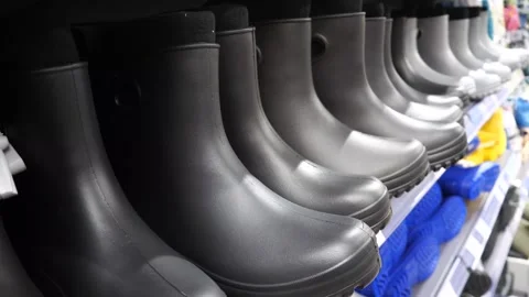 Rubber black work boots standing in a row on a store shelf. Stock Footage 288725867