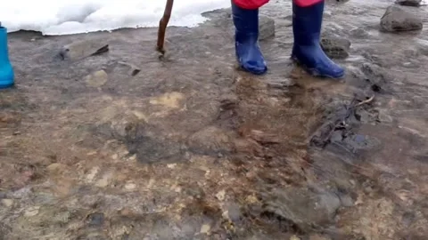 Rubber boots walking in spring melting creek  Vidéo 172556156