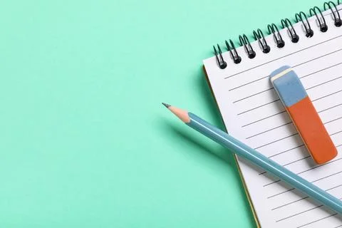 Rubber eraser with notebook and pencil on turquoise background, closeup Stock Photos