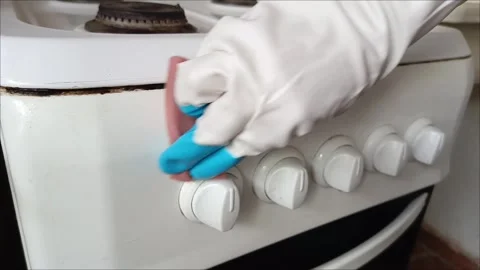 Rubber-gloved hands sponge clean the control panel of the gas stove Stock Footage 311697125