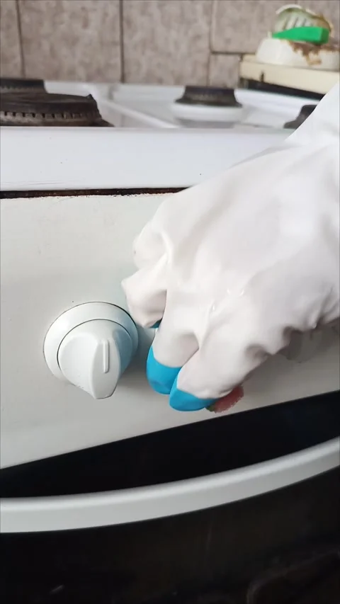 Rubber-gloved hands sponge clean the control panel of the gas stove Video stock 311697131