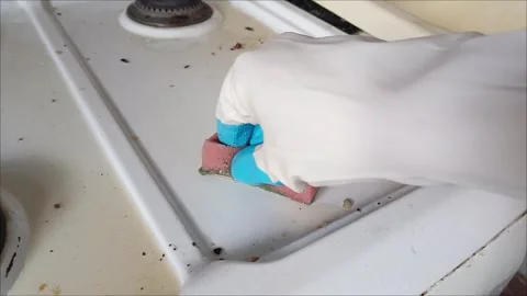 Rubber-gloved hands sponge clean a dirty gas stove 動画素材 311697154