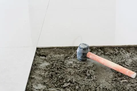 Rubber hammer on floor tile installation for house building Fotos Stock