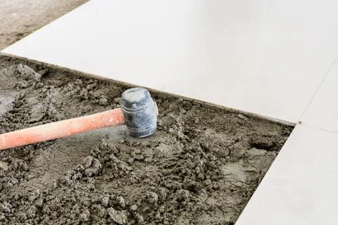 Rubber hammer on floor tile installation for house building Stock Photos