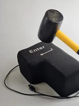 Rubber Mallet Above Oversized Enter Key as Computer Stress Concept Stock Photos
