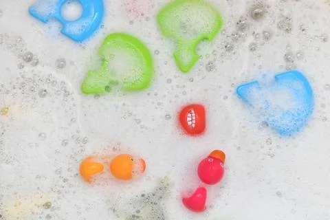 Rubber multicolored toys in a bubble bath Stock Photos
