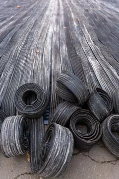 Rubber rolls and flat strips are arranged on an industrial surface near a m.. Stock Photos