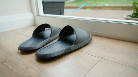 Rubber slide sandals worn by man preparing to step into backyard space. Bare Stock Footage 336547385