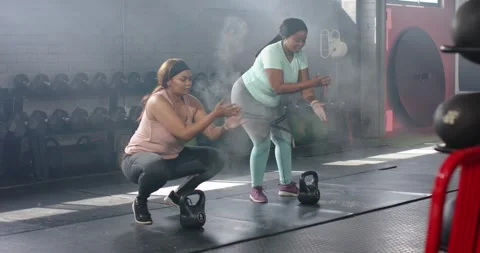Rubbing chalk and clapping, Diverse female friends hopping in squat at gym for Stock Footage 342233280