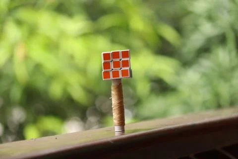 A Rubics cube placed over a sewing thread placed in a dusty floor Stock Photos